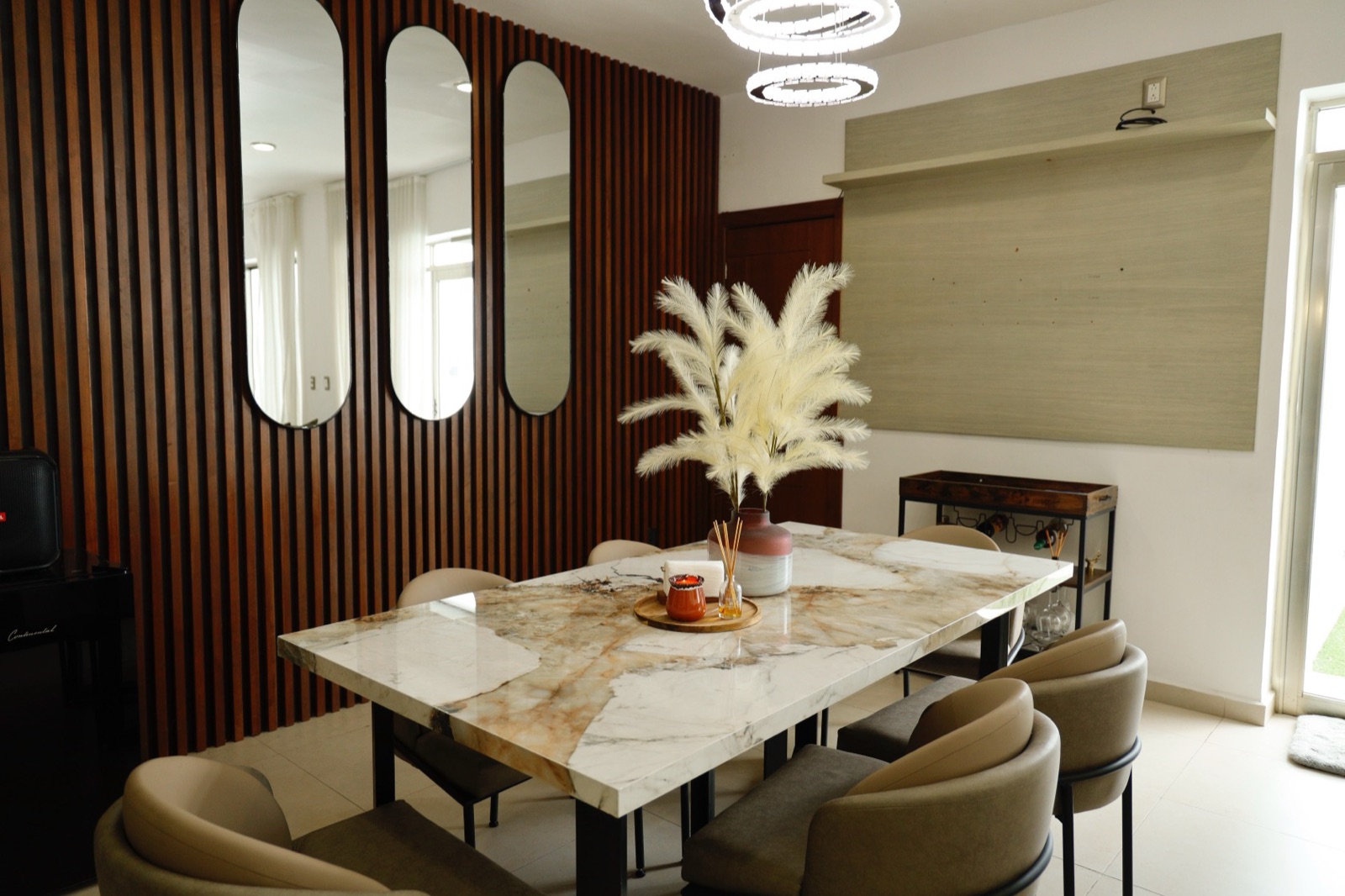 Comedor remodelado con muro de listones de madera y mesa de mármol, Casa Cluster 12