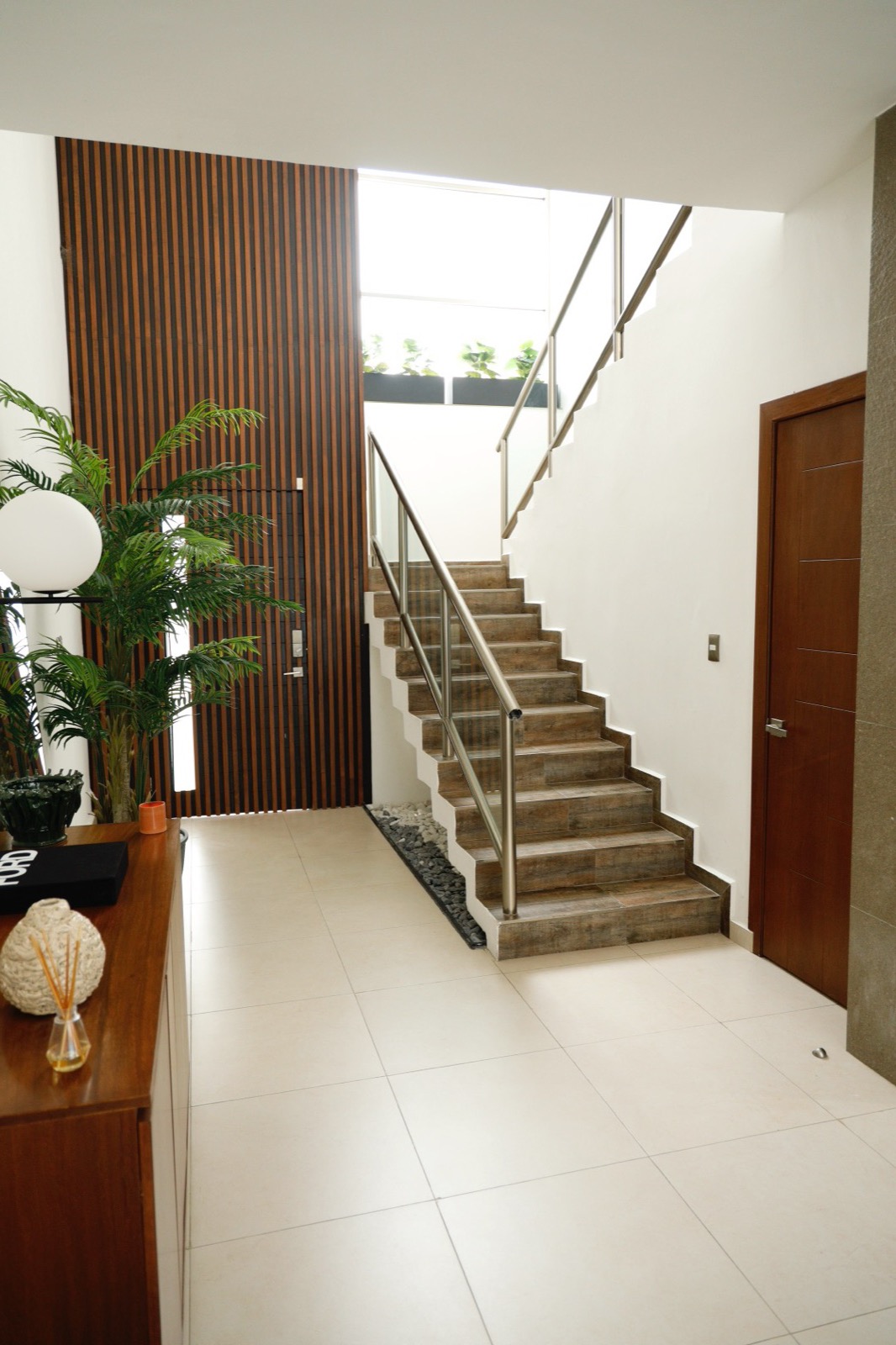 Escalera con peldaños de madera y muro de listones a doble altura, Casa Cluster 12