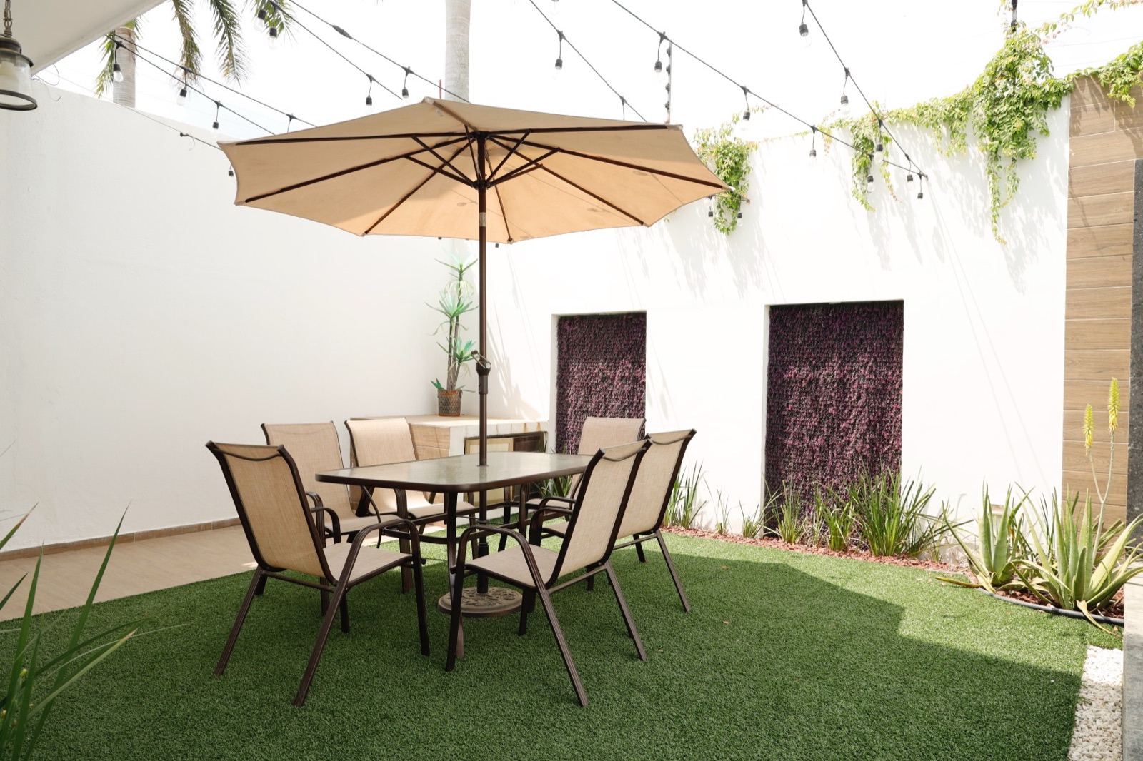 Jardín con terraza, sombrilla y muros verdes de casa entregada en Villahermosa